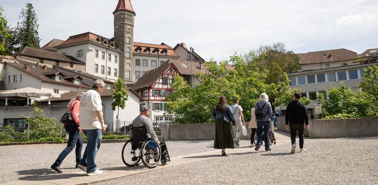 Personen beim inklusiven Stadtrundgang von Pro Infirmis auf einem Platz in Frauenfeld Personen beim inklusiven Stadtrundgang von Pro Infirmis auf einem Platz in Frauenfeld