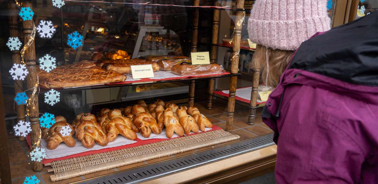 Une personne se tient devant une vitrine avec des bonshommes de St-Nicolas