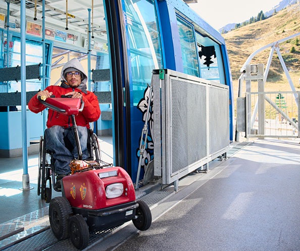 Ein Mann im Rollstuhl fährt mit dem Swiss-Trac aus der Luftseilbahn.